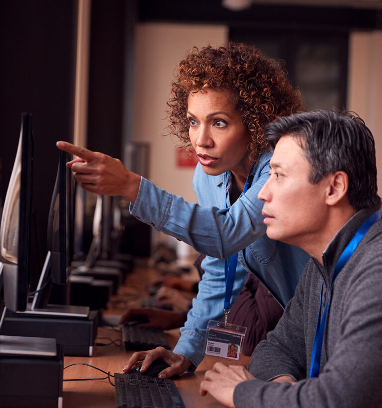 Male and female employees look at data on a computer